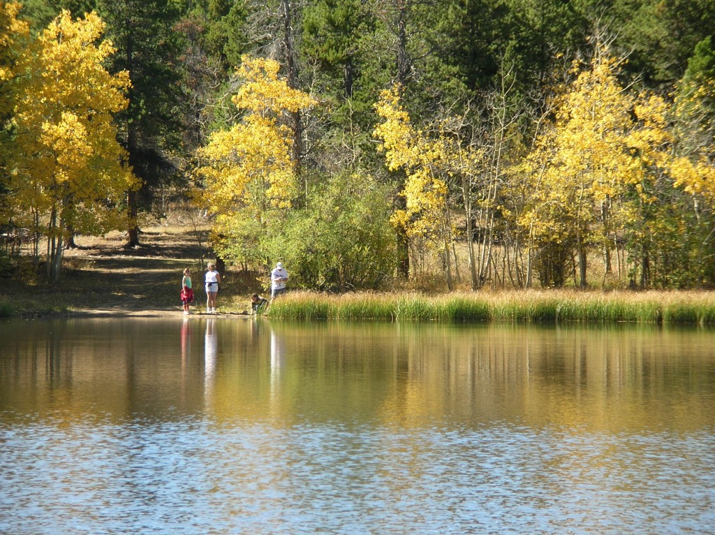 Four people standing on the shore of Mud Lake in the fall