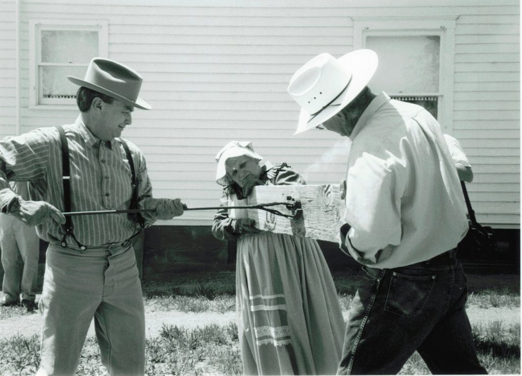 Black and white photo of Ron Stewart using a branding iron
