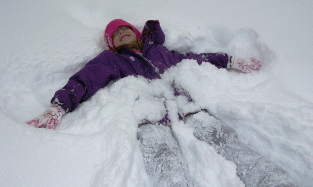 Little girl making a snow angel.