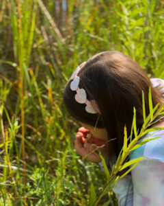 A young girl pauses to smell the flowers during a nature adventure with her family at Pella Crossing.