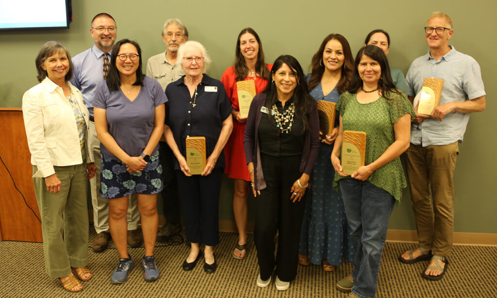 Group photo of award winners holding their plaques