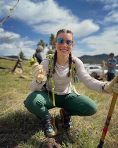 A smiling woman shows the camera a plant pulled from its root.