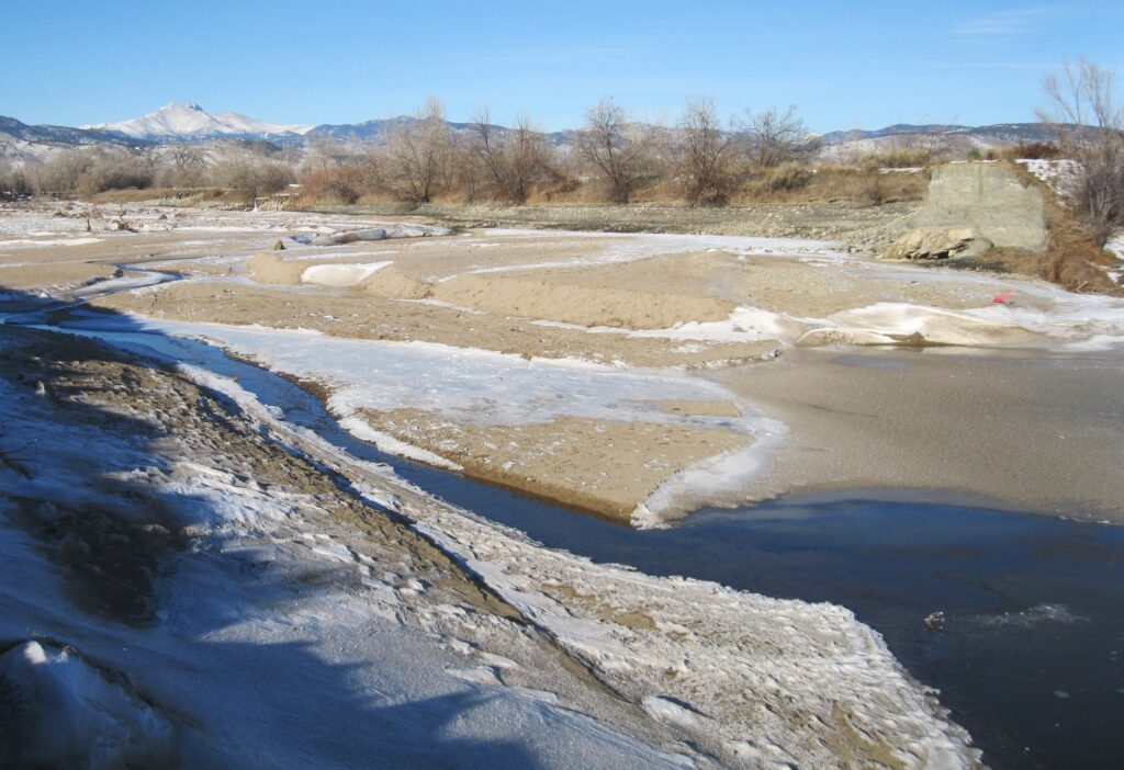 Aerial view of St. Vrain Creek showing extensive flood damage after the 500-year flood event in 2013, with eroded banks, debris, and altered river channels.