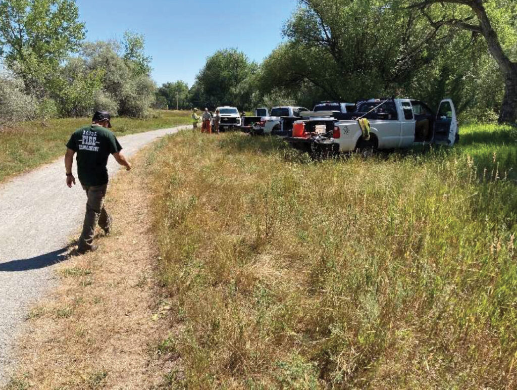 Parks & Open Space staff member approaches a work site full of partner agency vehicles