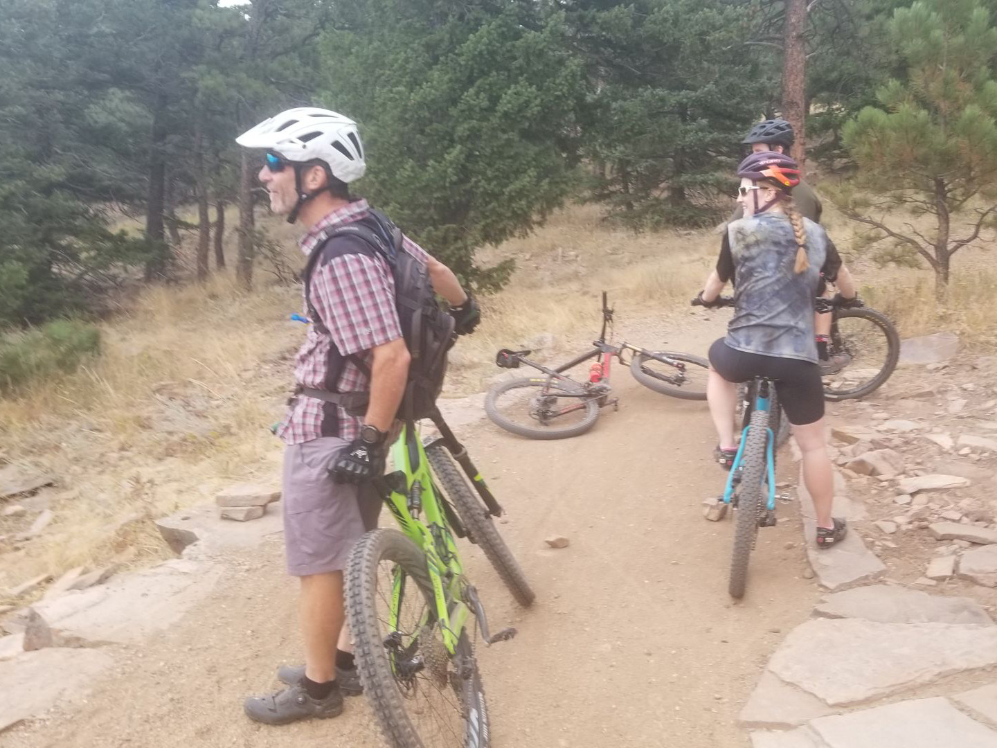 Three mountain bikers looking for trash on a trail