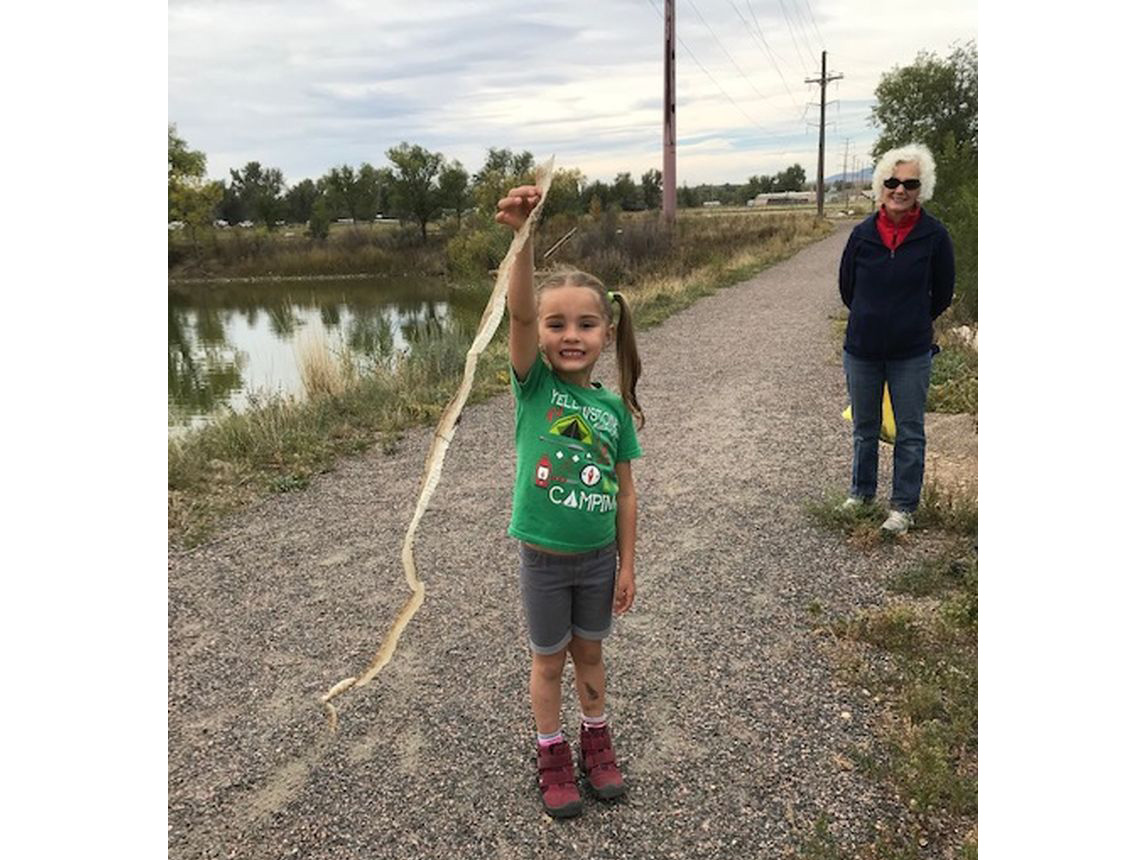 A young girl proudly shows a piece of trash she collected 