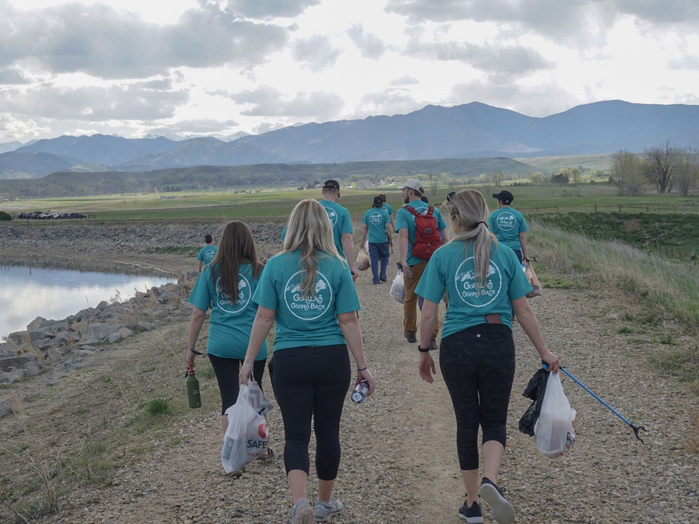 A large group of people walking along a trail collecting trash